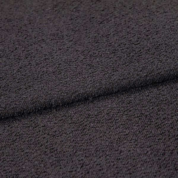 Dark charcoal looped fabric, forming a shallow horizontal fold, close-up studio view emphasizing coarse, pebble-like texture under even, neutral lighting.