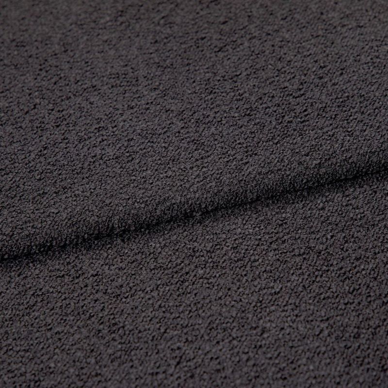 Dark charcoal looped fabric, forming a shallow horizontal fold, close-up studio view emphasizing coarse, pebble-like texture under even, neutral lighting.