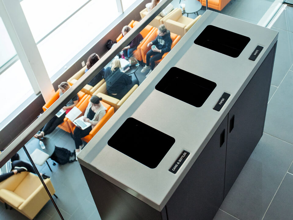 triple trash and recycling container with a flat lid made from durable powder coated steel in a busy college campus
