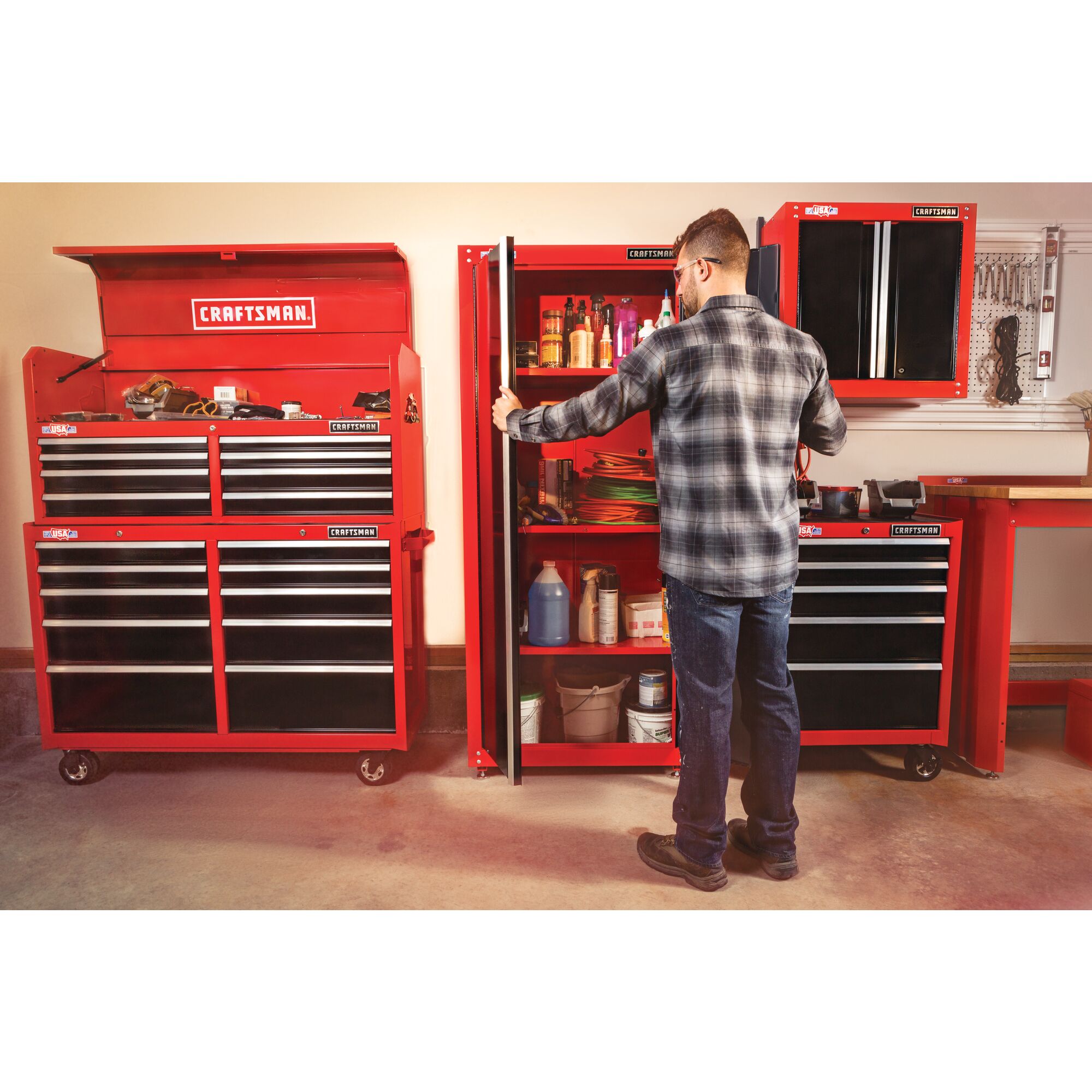 32 inch Wide freestanding tall garage storage cabinet being used by a person to keep items.