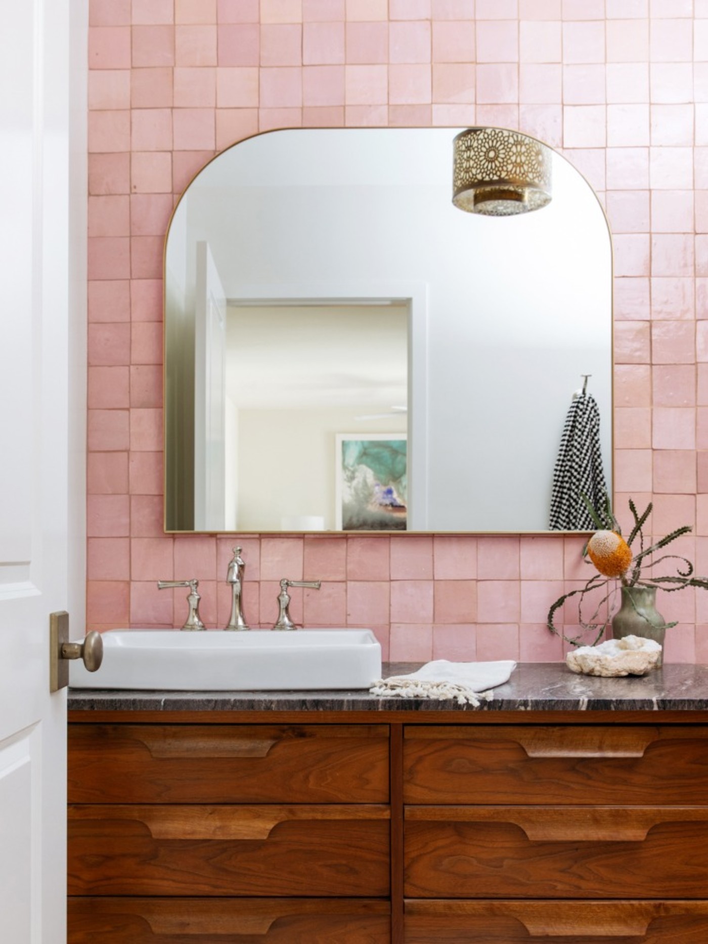 a bathroom with pink tiled walls and a wooden vanity.