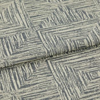 Woven upholstery fabric, cream base with gray, hand-drawn concentric-square pattern, folded over itself; photographed close-up under neutral studio lighting, showing textured weave and a layered edge.