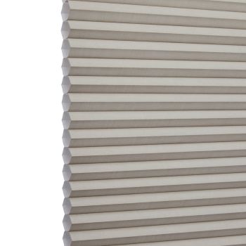Cellular (honeycomb) window shade, beige pleated fabric hanging fully lowered with hexagonal cells, closed and gently filtering light; close-up interior view focusing on repeating horizontal folds.