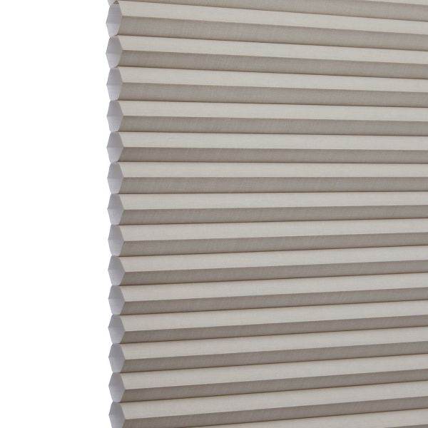 Cellular (honeycomb) window shade, beige pleated fabric hanging fully lowered with hexagonal cells, closed and gently filtering light; close-up interior view focusing on repeating horizontal folds.