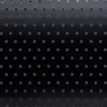 Black roller blind with regular small circular perforations — lowered and closed, the holes subtly admit faint light — set in a dim interior against a smooth background with a gentle top gradient.
