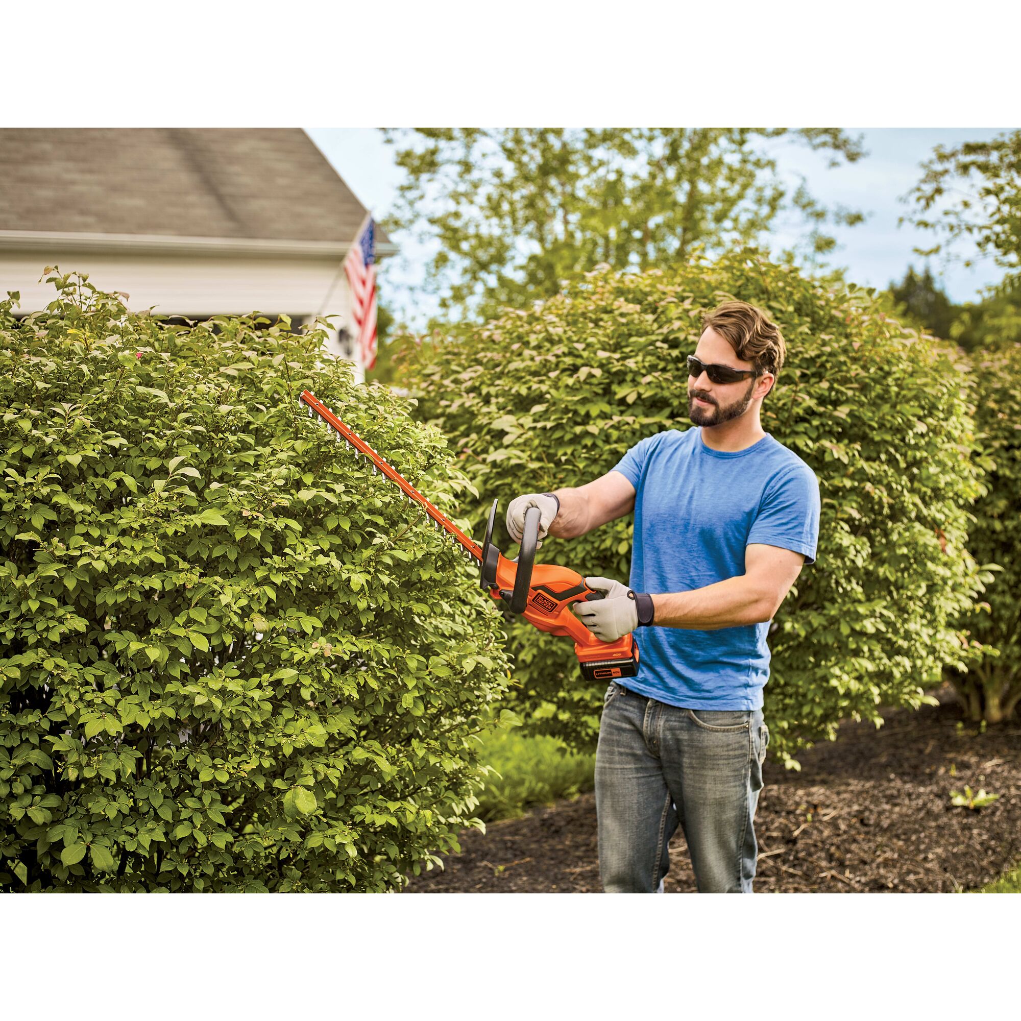 Man using 22 Inch 40 Volt Max Hedge Trimmer to trim a bush.