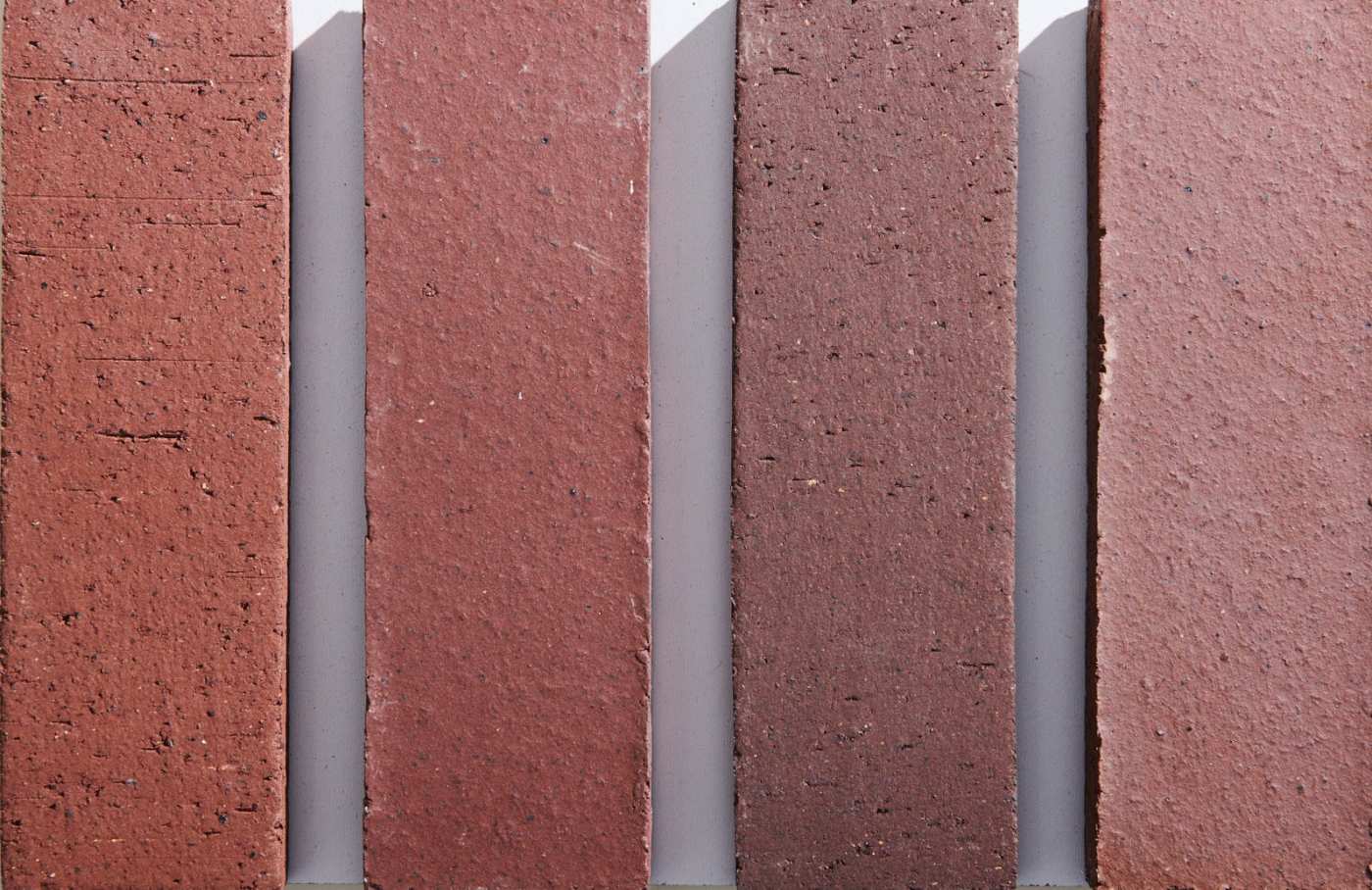 a row of red and brown bricks on a white surface.