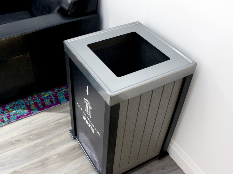 overhead view of waste opening lid in a recycled plastic lumber container with a large waste body sign in an upscale office