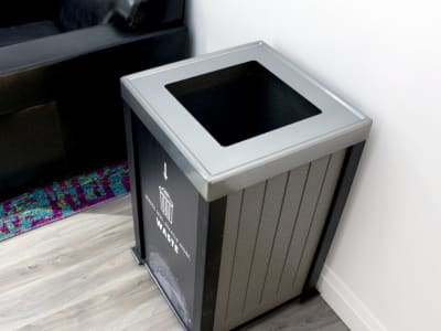 overhead view of waste opening lid in a recycled plastic lumber container with a large waste body sign in an upscale office