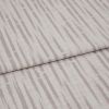 Patterned upholstery fabric (folded), pale mauve vertical dash stripes and textured weave; overlapping folded edge across the frame; close-up on a flat surface under soft, neutral lighting.