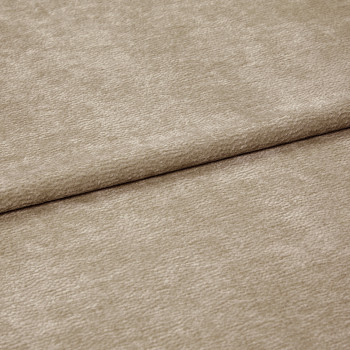 Beige textured fabric folded diagonally, overlapping along a soft crease — close-up of a chenille-like upholstery or curtain textile with subtle ribbed pile, even neutral lighting on a flat surface.
