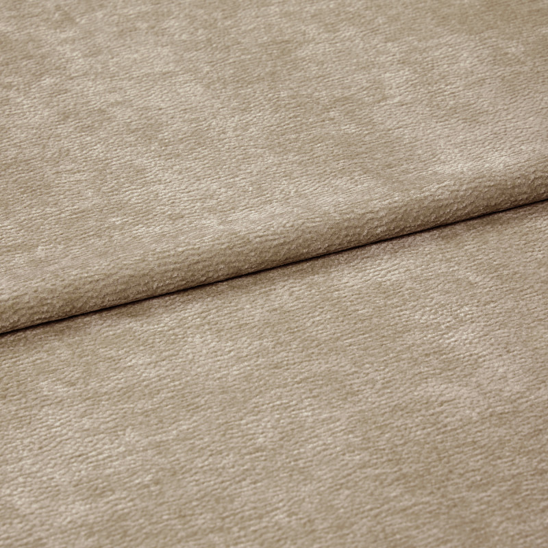 Beige textured fabric folded diagonally, overlapping along a soft crease â€” close-up of a chenille-like upholstery or curtain textile with subtle ribbed pile, even neutral lighting on a flat surface.