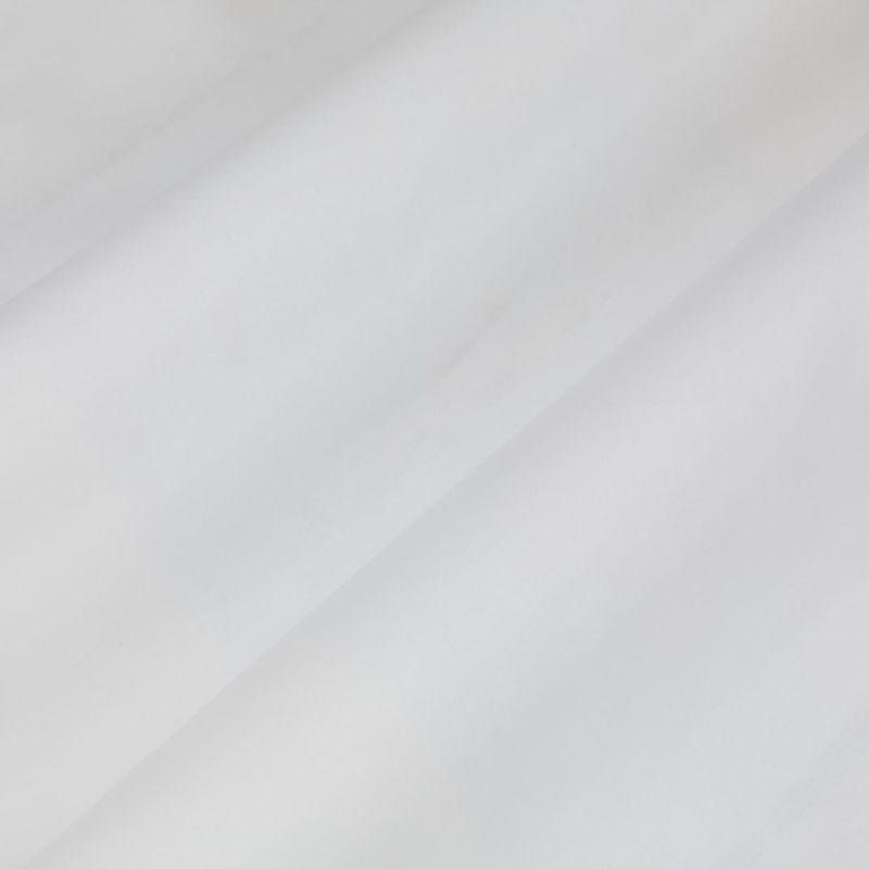 Sheer white curtain with diagonal soft folds draping across the frame, gently filtering daylight and casting subtle shadows in a bright, softly lit interior.