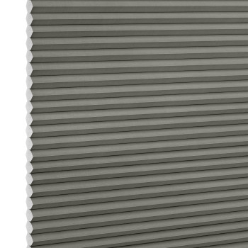 Grey honeycomb (cellular) pleated blind, vertically positioned with visible hexagonal cells at left edge; lowered and closed, evenly blocking light in a close-up, neutral studio-lit view.