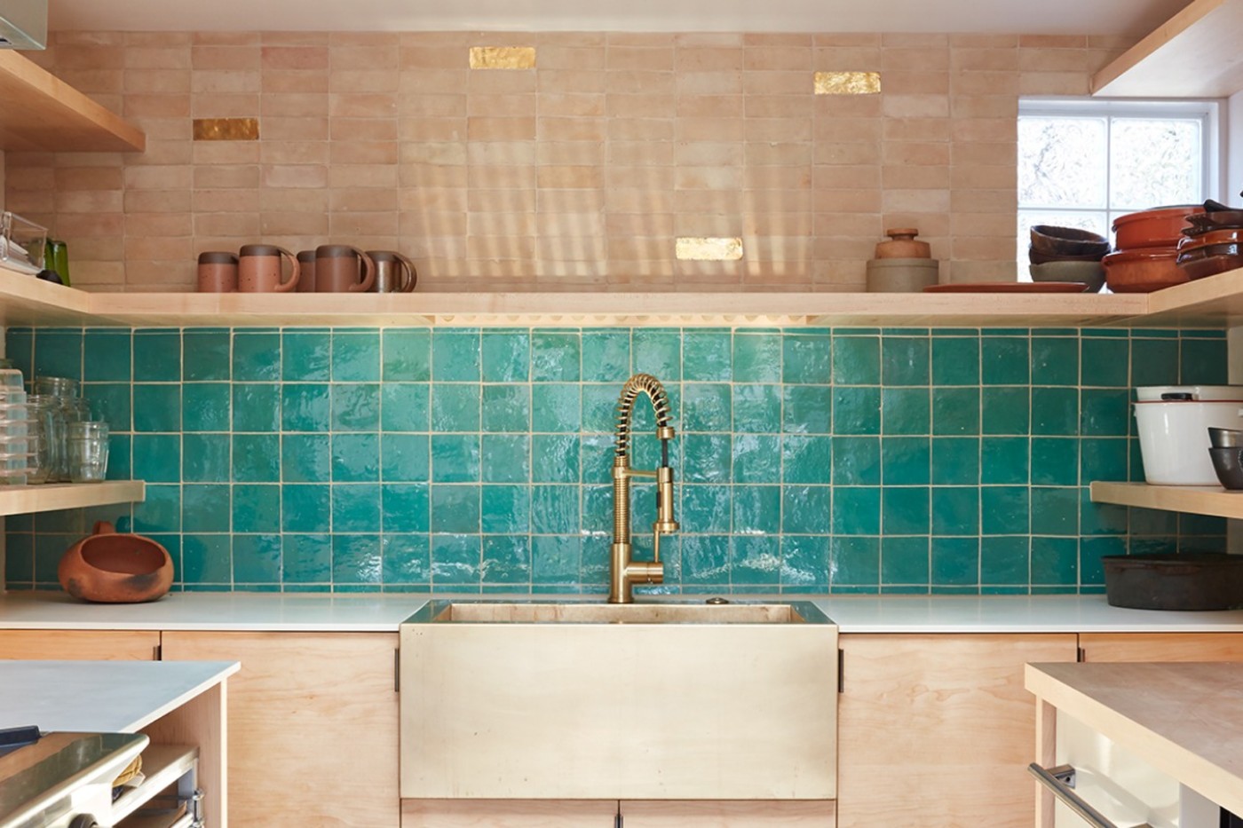 a kitchen with a green tiled backsplash wall.