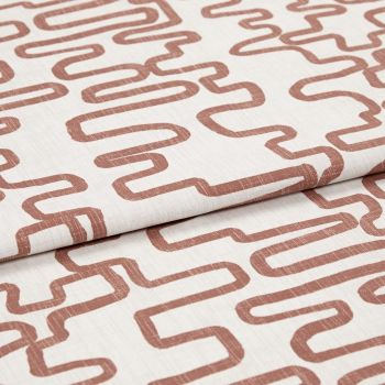 Folded off-white linen fabric printed with rust-colored, continuous squiggle pattern; fabric is layered and slightly creased, shown in close-up under soft studio lighting.