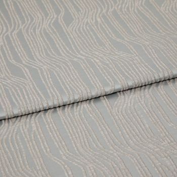 Folded patterned fabric with raised, parallel wavy chenille stripes in pale beige on a muted gray-green background; lying flat with a central fold under soft studio lighting, close-up view.