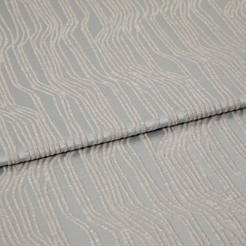 Folded patterned fabric with raised, parallel wavy chenille stripes in pale beige on a muted gray-green background; lying flat with a central fold under soft studio lighting, close-up view.