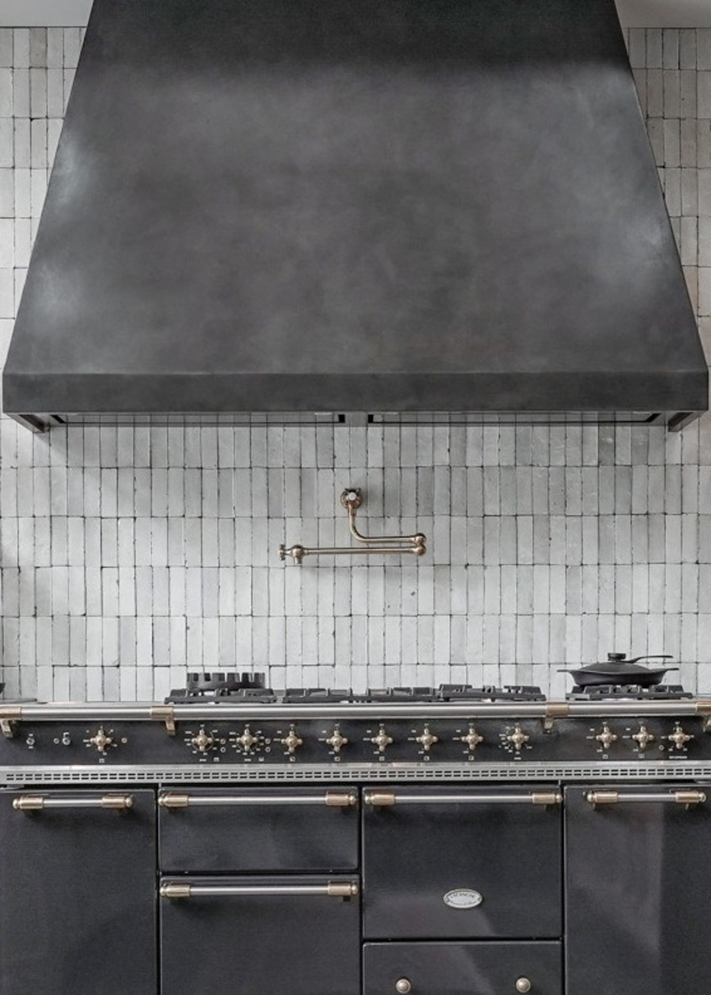 a kitchen stove and hood with white tile backsplash.