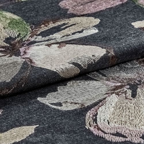 Dark grey jacquard fabric with large metallic-thread floral embroidery, folded and layered, showing textured, shimmering petals; close-up studio-lit view emphasizing weave, sheen, and textile detail.