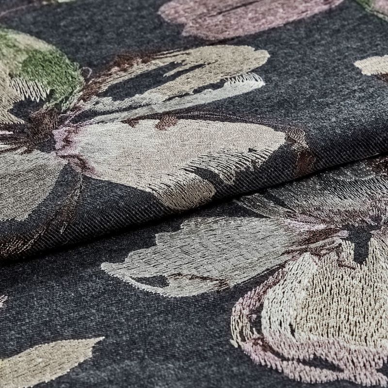 Dark grey jacquard fabric with large metallic-thread floral embroidery, folded and layered, showing textured, shimmering petals; close-up studio-lit view emphasizing weave, sheen, and textile detail.