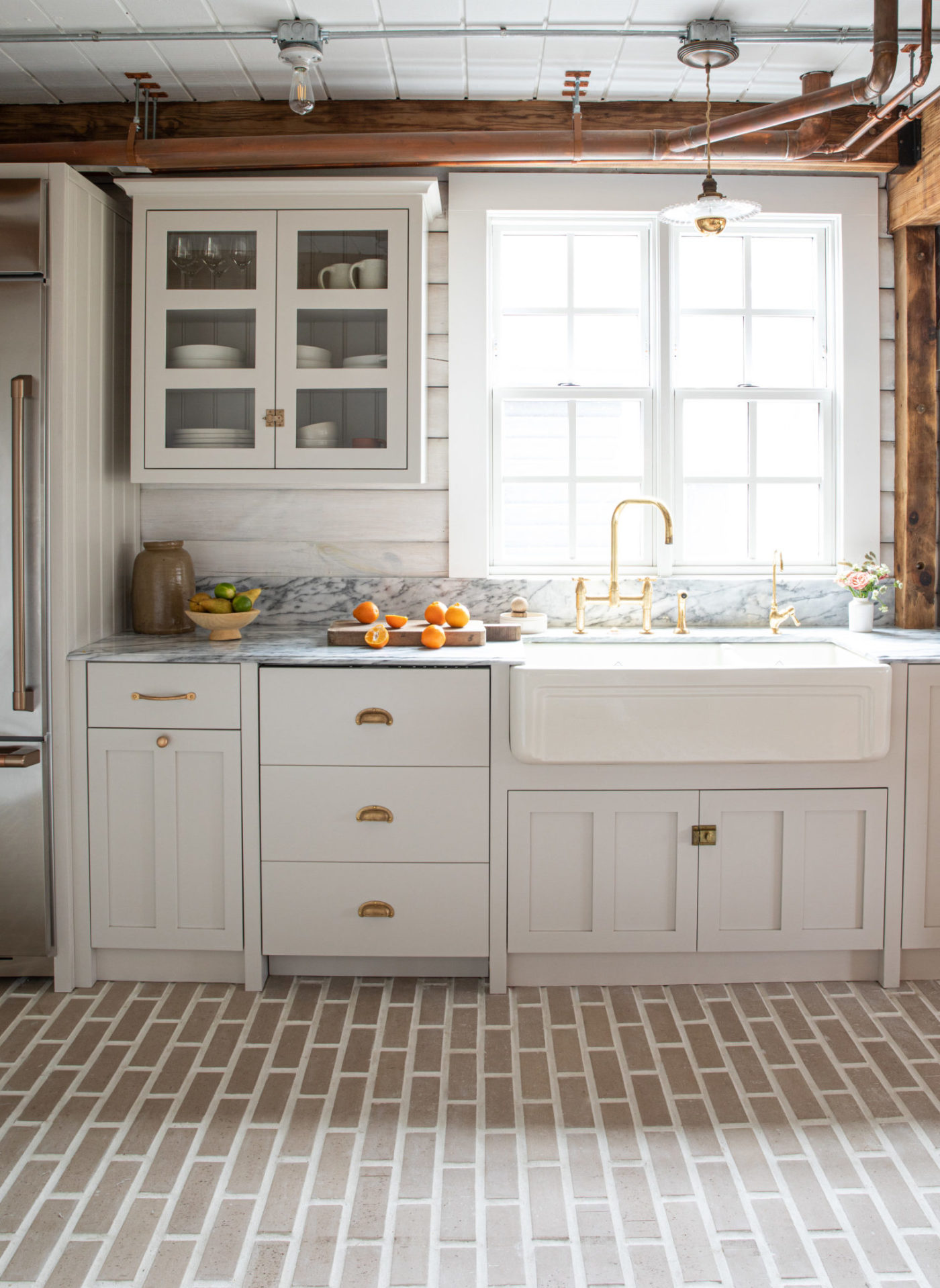 a white kitchen with a brick floor.