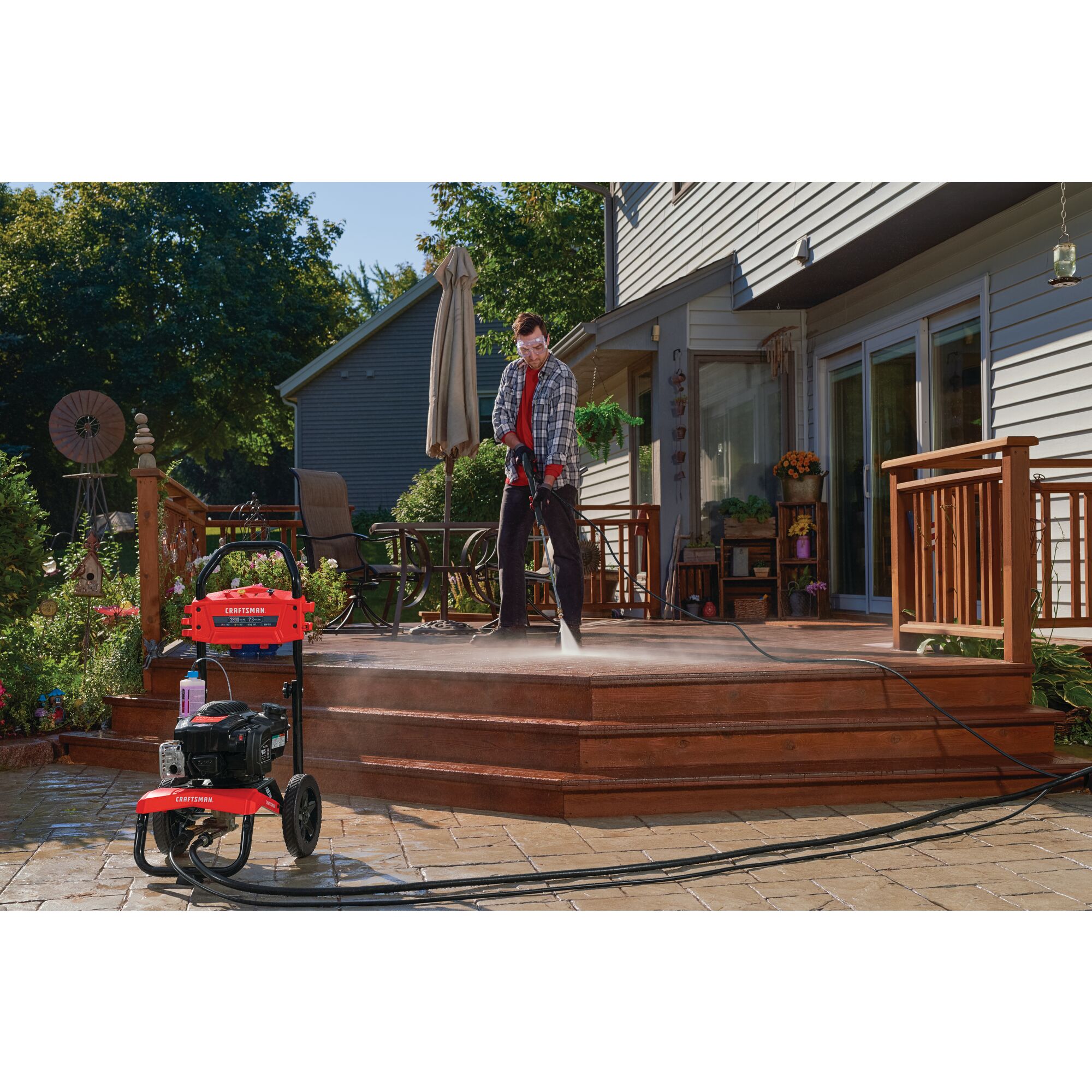 2800 MAX Pounds per Square Inch or 2 and three tenths MAX Gallons Per Minute Pressure Washer being used by person to wash wooden deck of house outdoors.