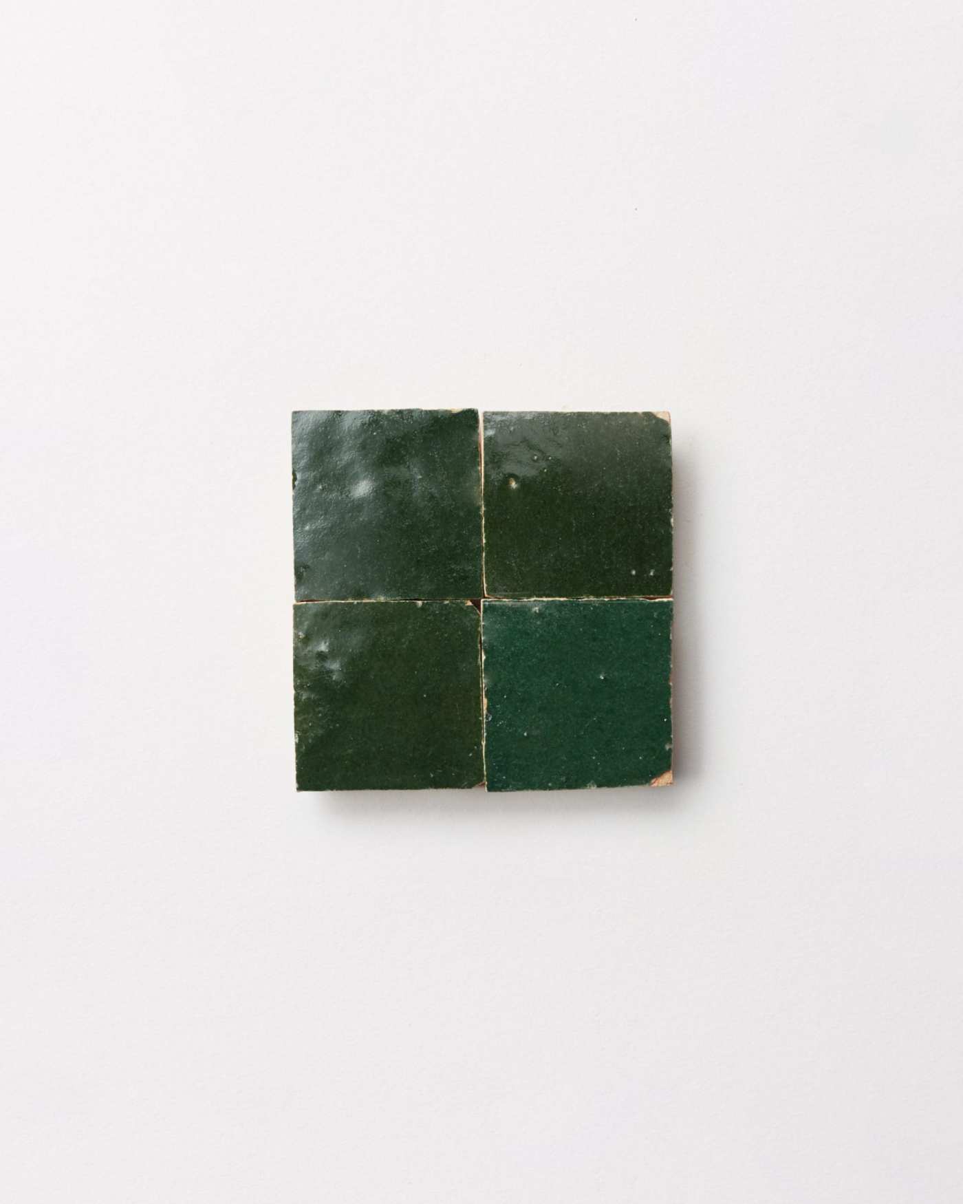 4 square pieces of green tile on a white surface.