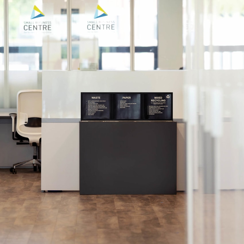 triple waste paper and recycling container in front of a business center with a sign frame