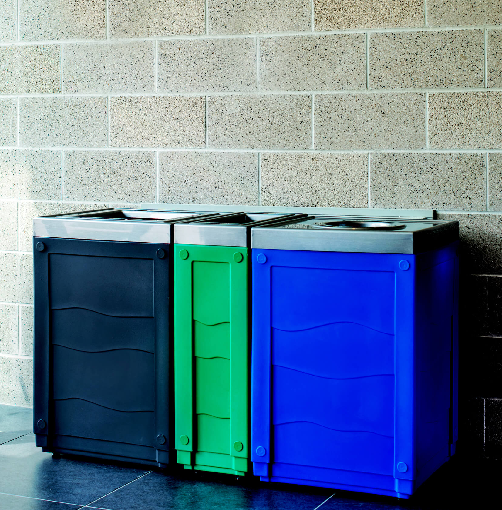 Trash and recycling station with color-coded bodies and pewter lids in a conference center foyer