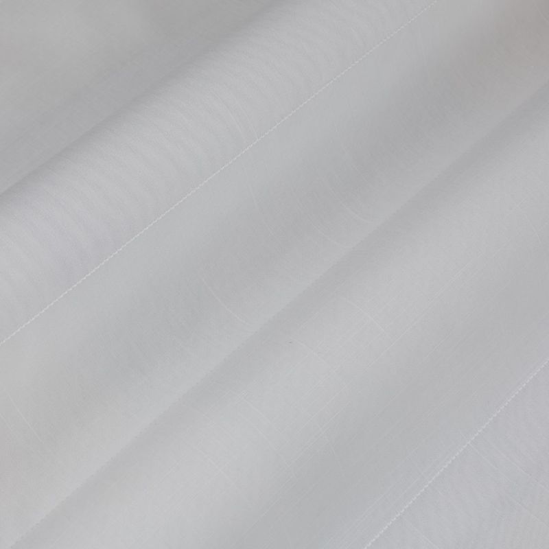 Object: white semi-sheer fabric (curtain-like) with stitched hem and faint grid texture. Action: layered into broad diagonal folds. Context: close-up view, soft diffuse lighting, neutral background.