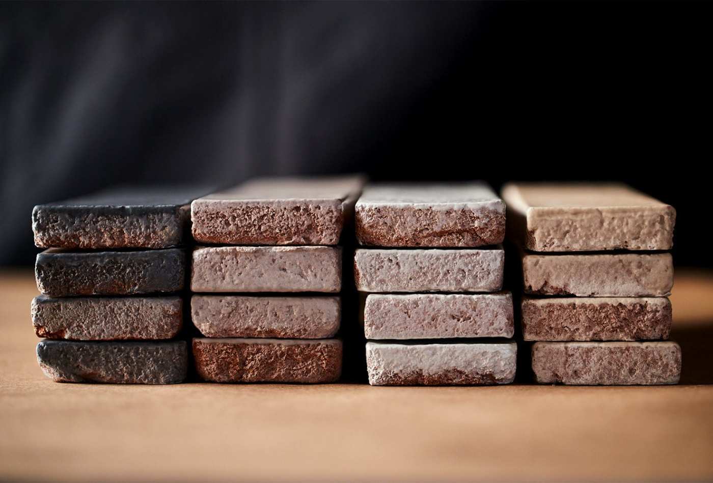 a stack of thin glazed bricks on a table with a black background.