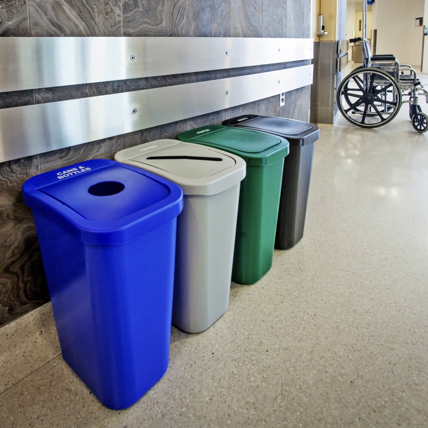 color-coded recycling and trash bins in a hospital hallway sitting beside a wheelchair