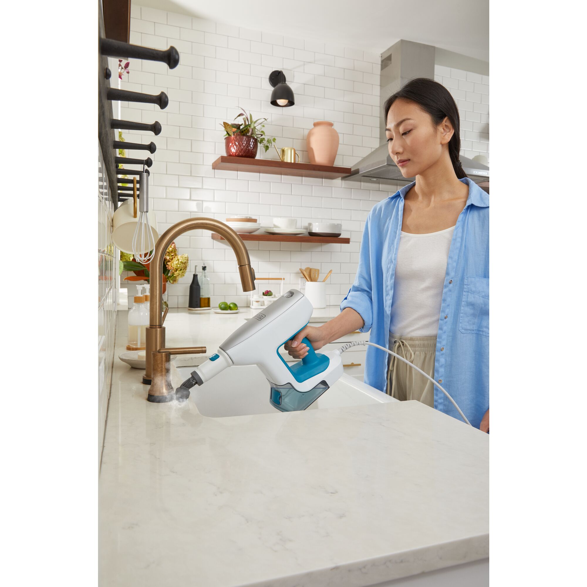 Woman filling up steam mop base with water from kitchen sink