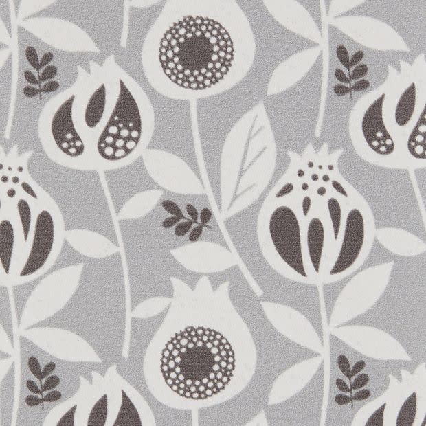 Wallpaper â€” light-gray, matte textured surface patterned with repeating stylized white and dark-gray pomegranate-like flowers and leaves; the motif repeats uniformly, covering a flat interior wall under even lighting.