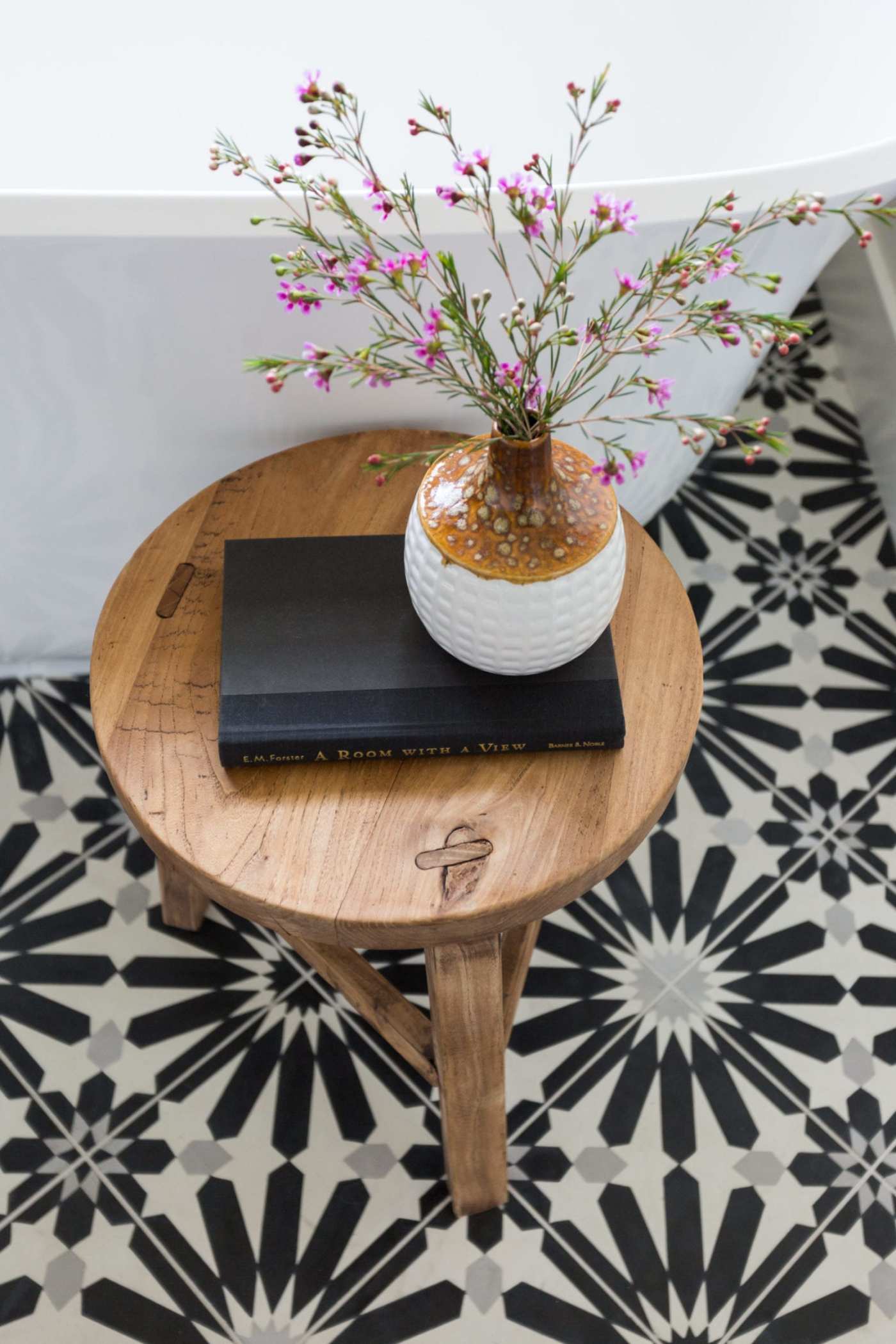 a black and white tiled bathroom with a wooden table and flowers.