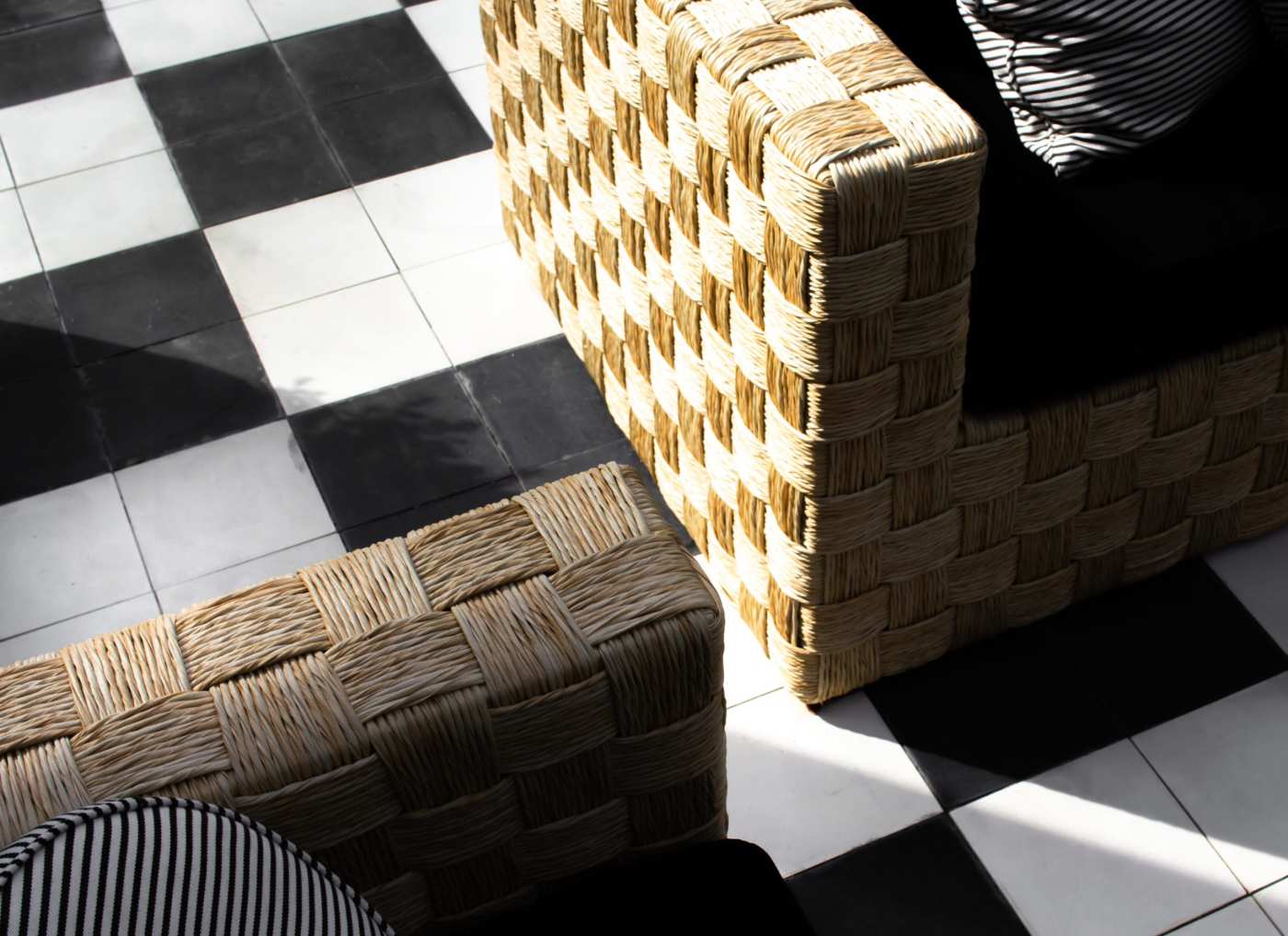 two wicker chairs on a black and white checkered floor.