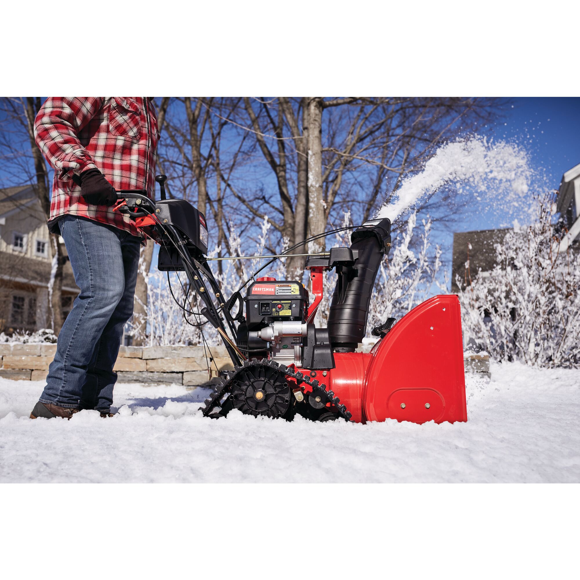 CRAFTSMAN 208CC Electric Start Track Drive Snow Blower blowing snow in the yard in side view in plaid shirt and jeans