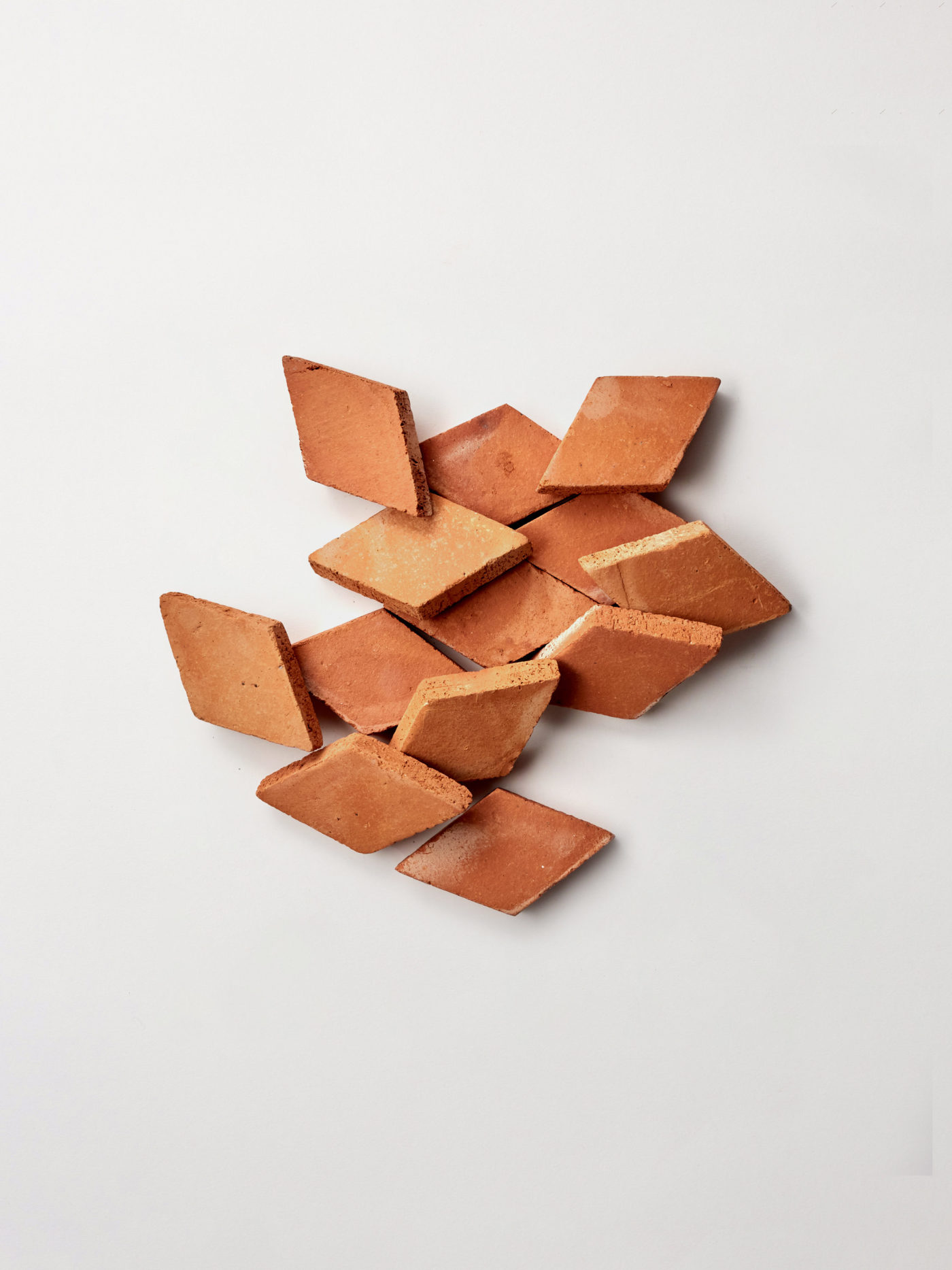 a group of red tiles piled on a white surface.