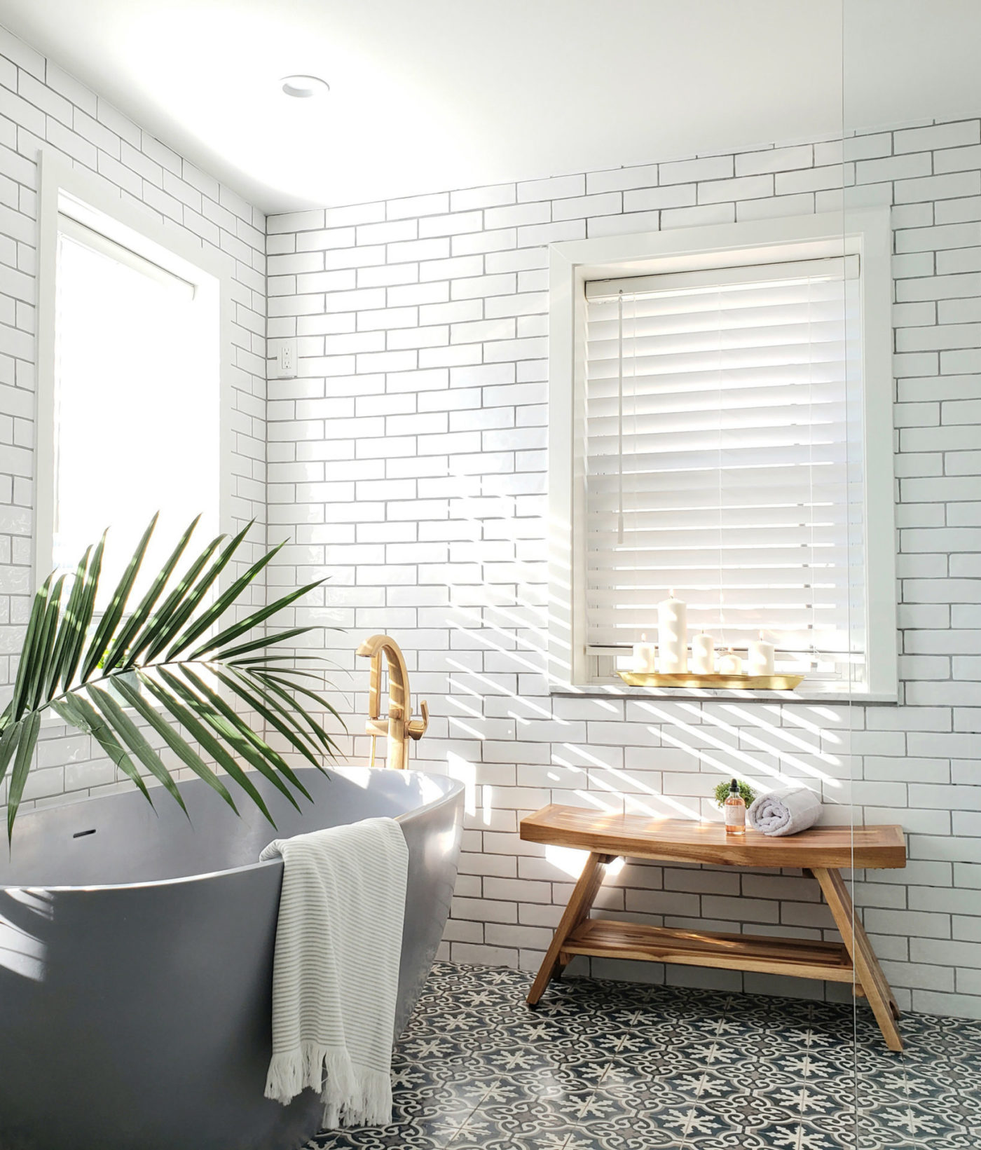 a blue and white tiled bathroom with a tub and a plant.