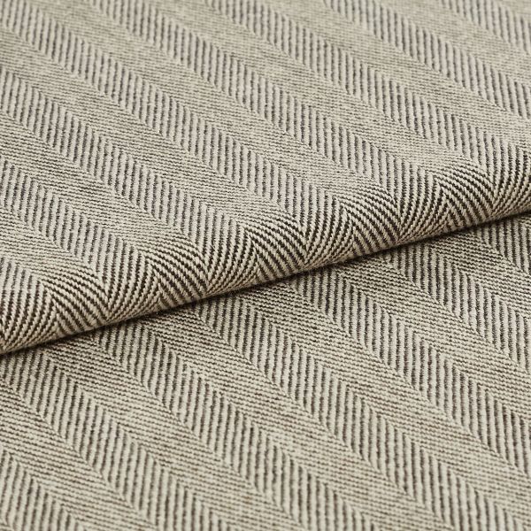 Folded beige-and-brown woven fabric with diagonal herringbone ribs; folded over itself forming parallel raised ridges; close-up on a flat surface under soft, neutral lighting.