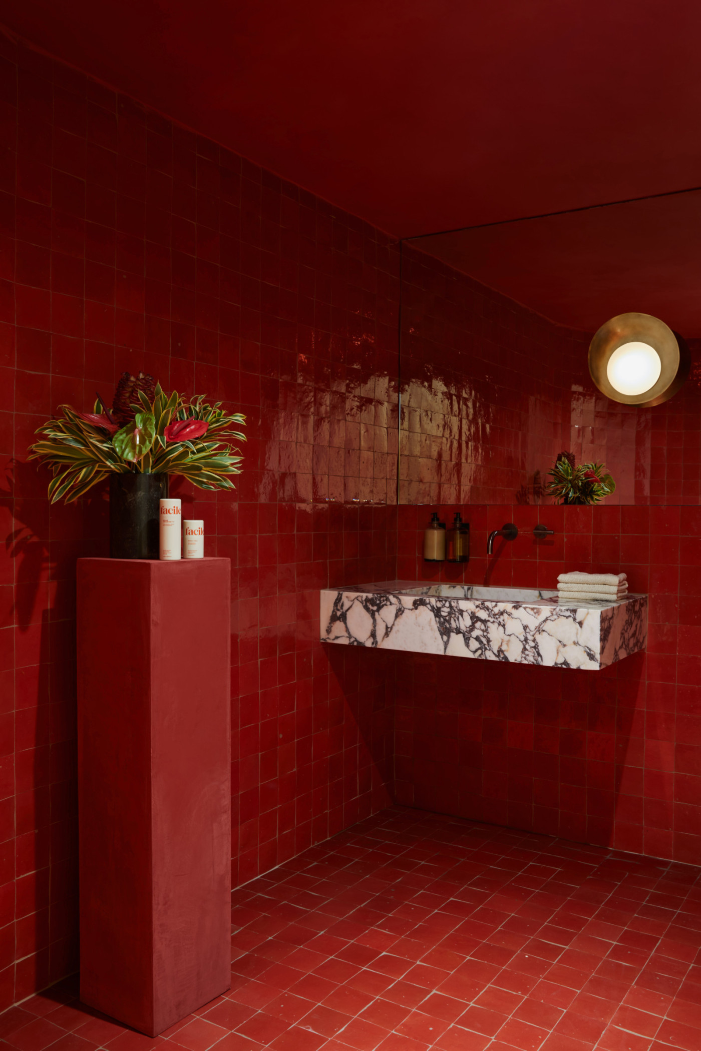 a red tiled bathroom with a sink and a mirror.