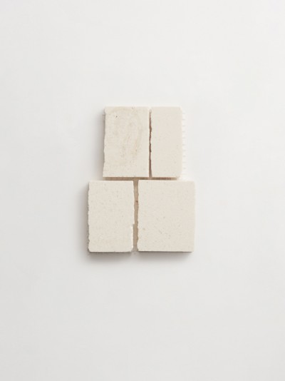 four squares of white soap on a white surface.