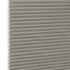 Gray-beige cellular honeycomb blind, pleated with visible hexagonal cell edges at left, closed and filtering light; close-up view with neutral, evenly diffused lighting and no visible room.