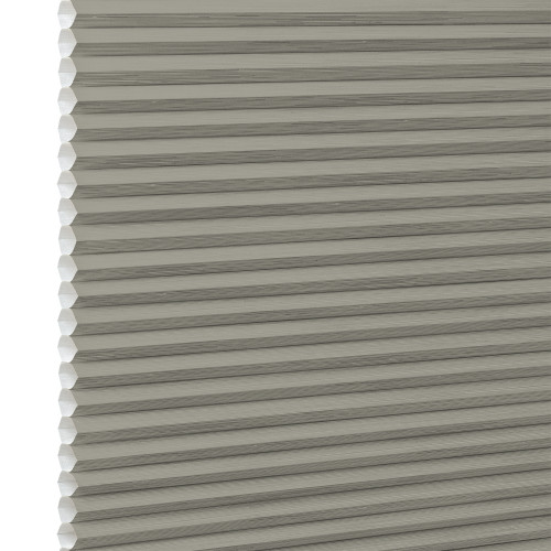 Gray-beige cellular honeycomb blind, pleated with visible hexagonal cell edges at left, closed and filtering light; close-up view with neutral, evenly diffused lighting and no visible room.