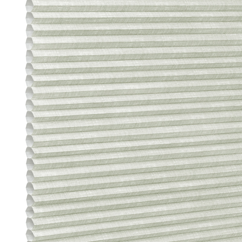 Pale green honeycomb (cellular) blind, fully lowered with visible hexagonal cells and textured fabric; closed, gently diffusing daylight; fills the frame against a bright neutral background suggesting an interior window.