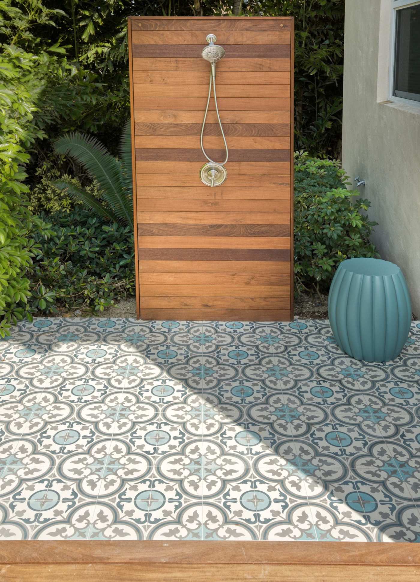 a tiled patio with a wooden deck and a shower.