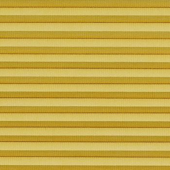 Horizontal cellular (honeycomb) pleated blind, closed with evenly spaced golden-yellow fabric folds and subtle texture; blocking light and insulating, filling the frame under warm diffuse lighting.