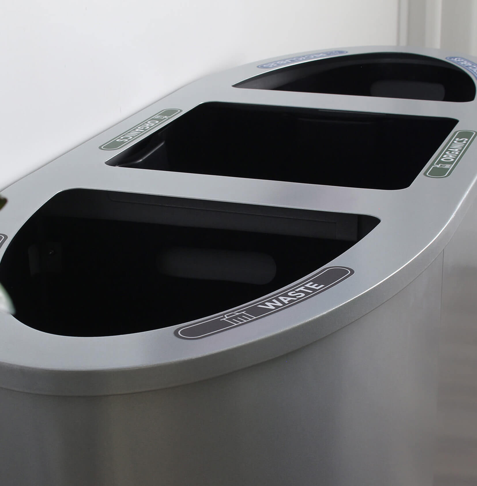 closeup of a triple opening trash and mixed recycling container showing the labels