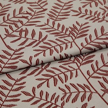 Woven beige upholstery fabric patterned with rust-red fern branches, folded and overlapped across the frame, close-up studio-lit view highlighting the woven texture and printed details.